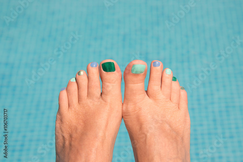 Close up on woman bare feet, blue water in the background