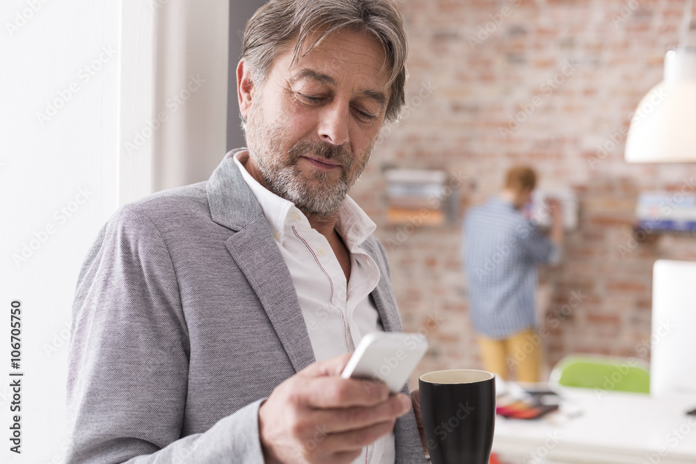 Businessman with cell phone and cup of coffee in office Businessman with cell phone and cup of coffee in office