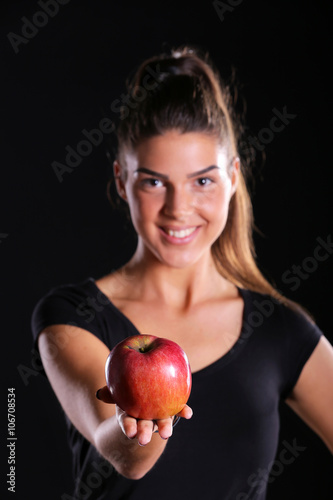 young girl holding an apple isolated on black background