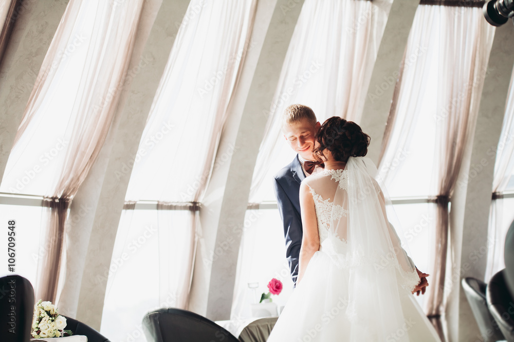 Naklejka premium Happy wedding couple, bride and groom posing in hotel