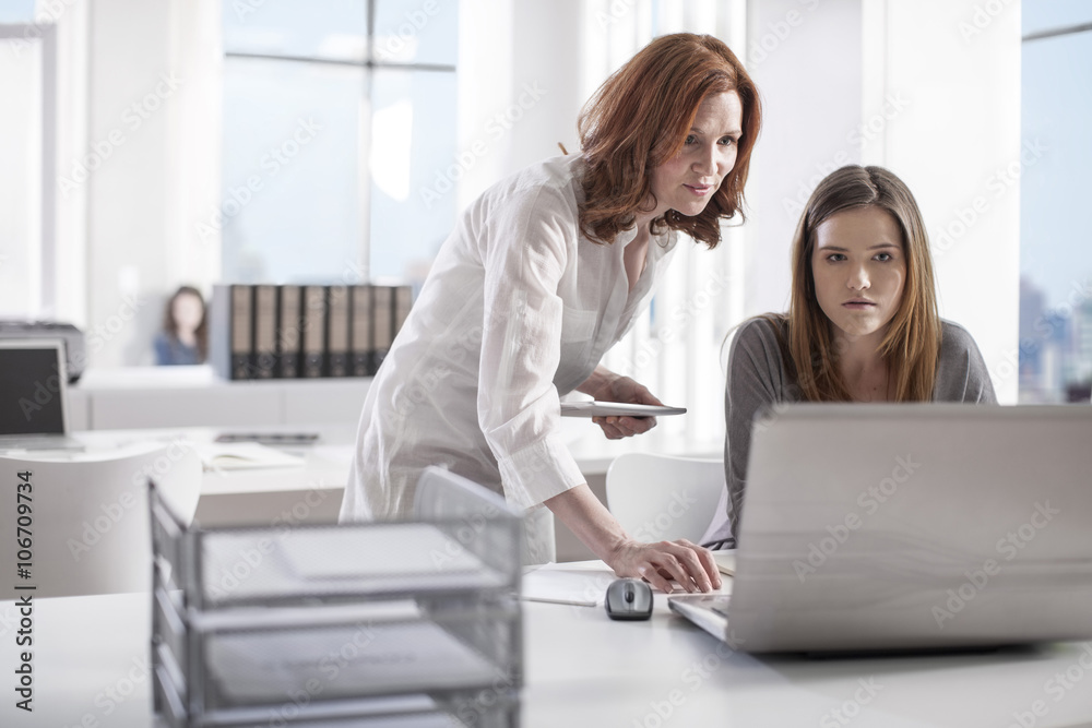 Two women in office working together on laptop Two women in office working together on laptop