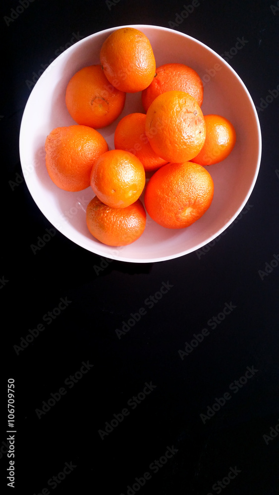 Tangerines in a white bowl on a black background