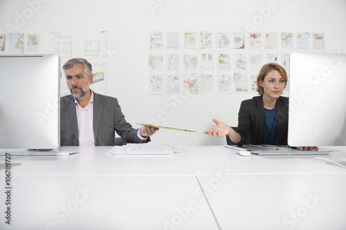 Two indifferent colleagues at their desks in an office photo
