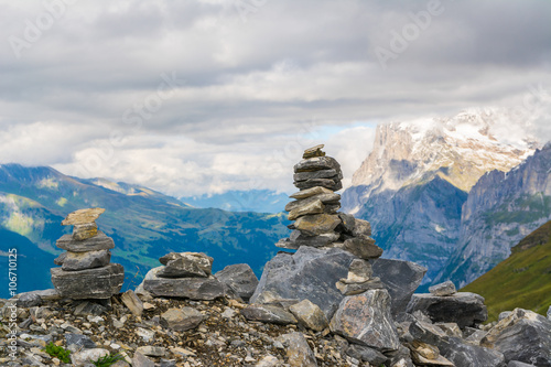 Leinwand Poster Small cairn with snow alpine mountains at background