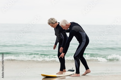 Senior man teaching woman to surf
