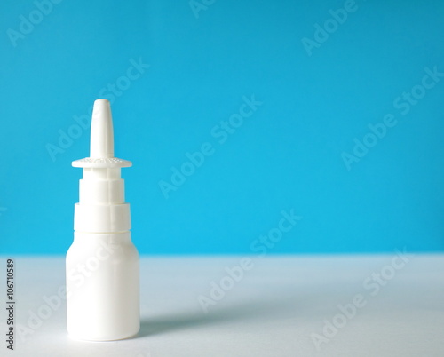 white nasal spray bottle closeup in front of blue background with a copy space