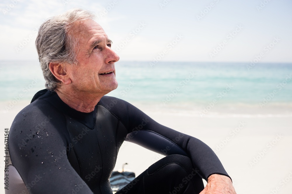 Happy senior man in wetsuit sitting on beach Happy senior man in wetsuit sitting on beach