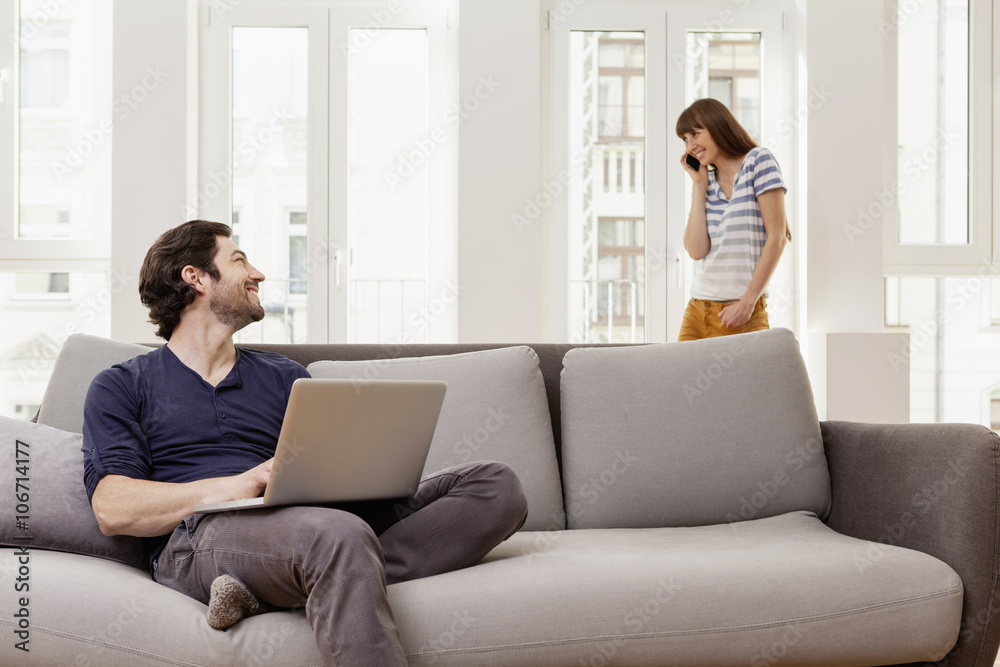 Couple using laptop and cell phone at home Couple using laptop and cell phone at home