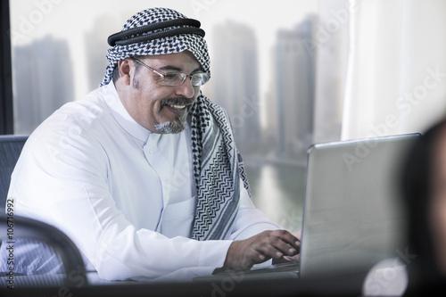 Middle Eastern businessman in office using laptop photo