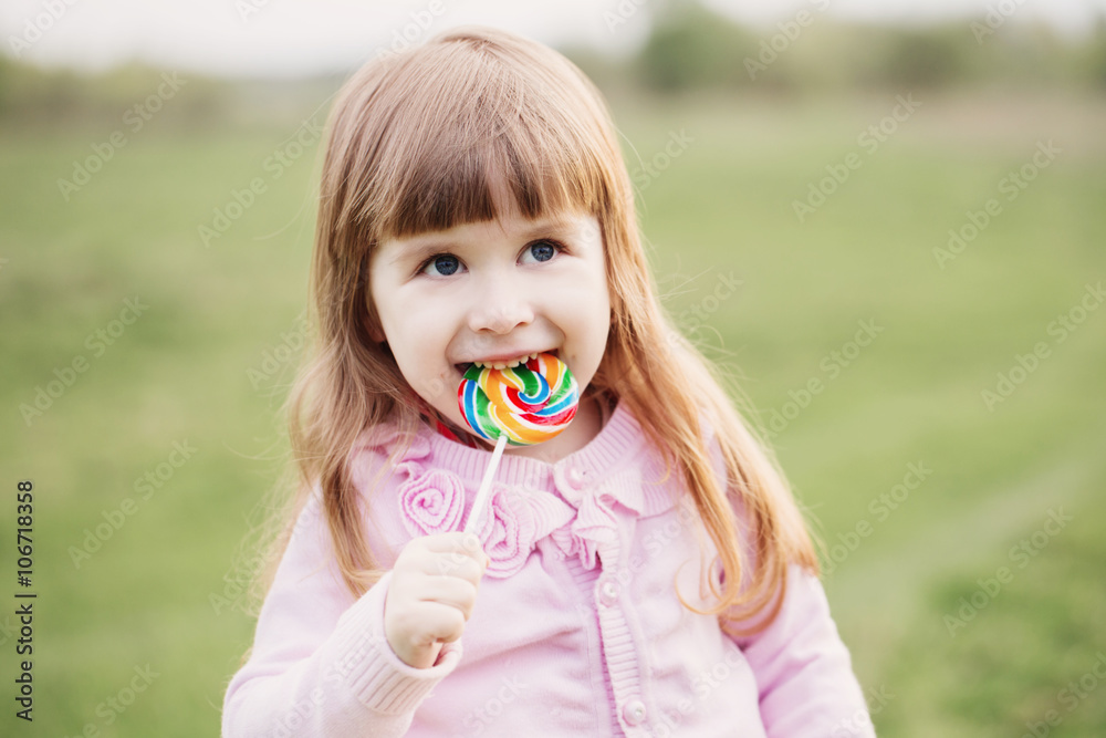 little girl holding lollipop in her hand