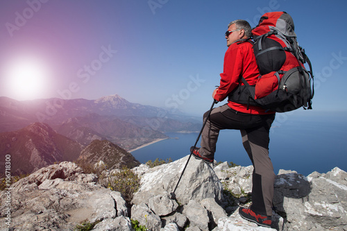 A traveler stands on top of a mountain and looks out to sea.