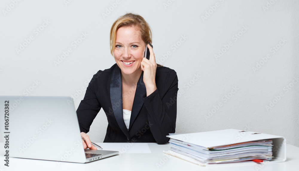Woman on desk with phone and laptop in business outfit Woman on desk with phone and laptop in business outfit
