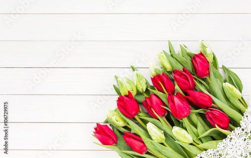 Red tulips bouquet decorated with lace on white wooden table. Copy space  top view