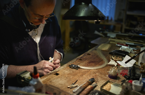 Violin maker repairing a bow photo