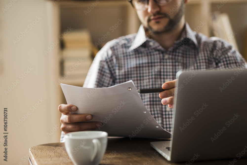 Man with document and laptop at desk Man with document and laptop at desk