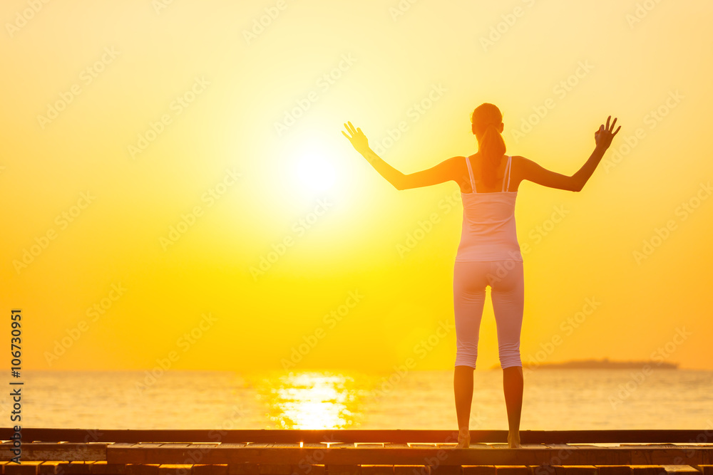 Fototapeta premium Young woman practicing yoga on the beach at sunset