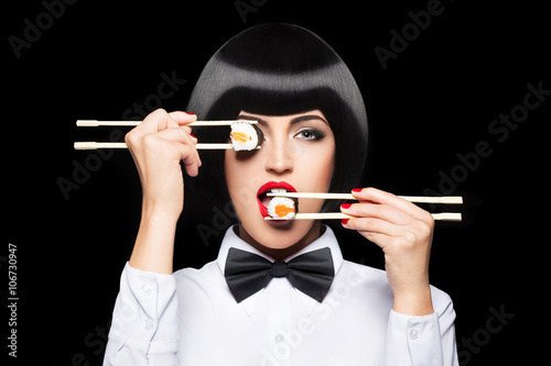 Beautiful woman eating sushi with chopsticks