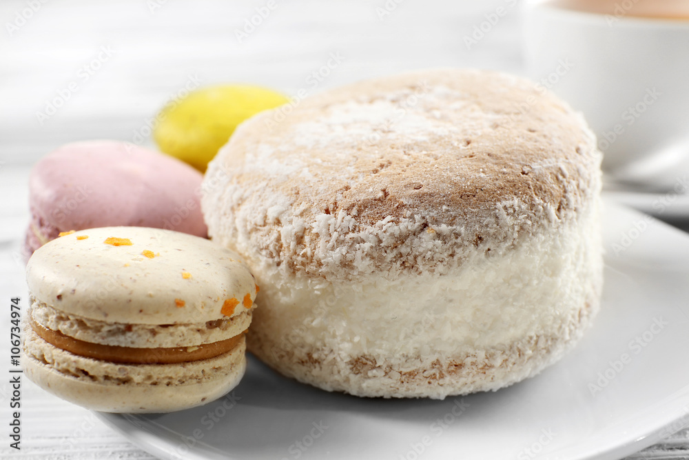 Delicious cake and macaroons on plate