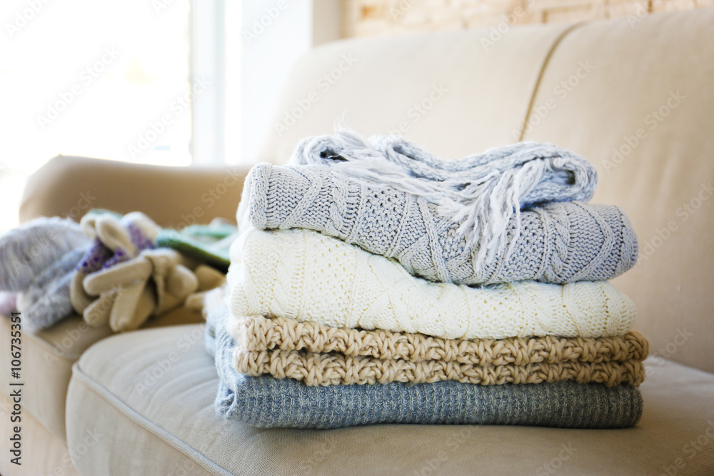 Stack of cozy knitted clothes on a sofa