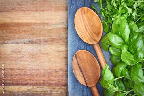 Basil, parsley and wooden spoons, culinary background