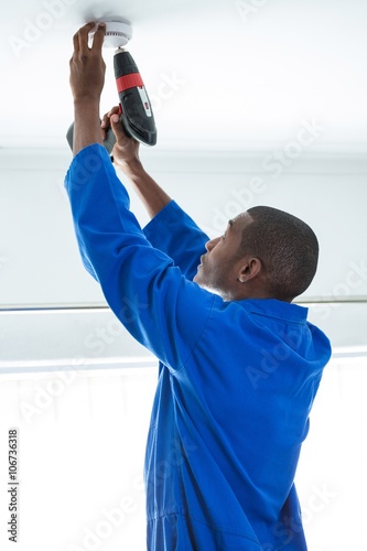 Handyman fixing the smoke detector with drill machine photo