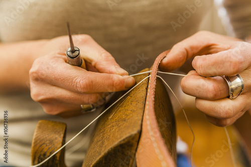 Woman sewing elastic fabric rubber band using lacing pony and awl