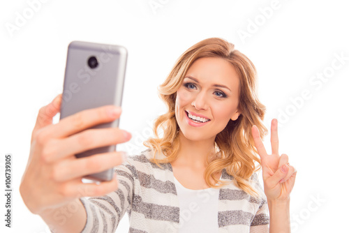 Woman with curly hair making selfie and showing two fingers