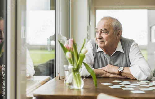 Portrait of senior man looking through window photo