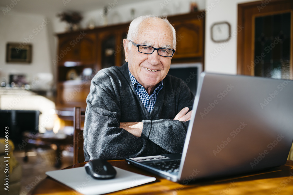 Portrait of smiling senior man with laptop at home Portrait of smiling senior man with laptop at home