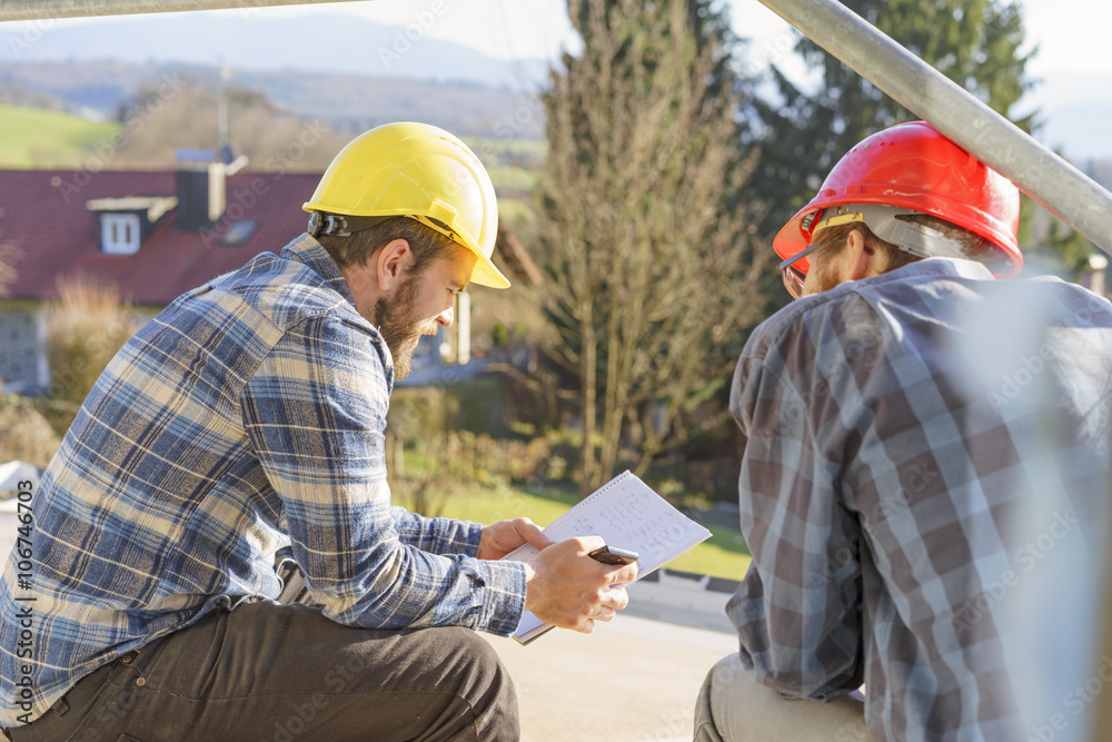 Two craftsmen looking at notes in construction site Two craftsmen looking at notes in construction site