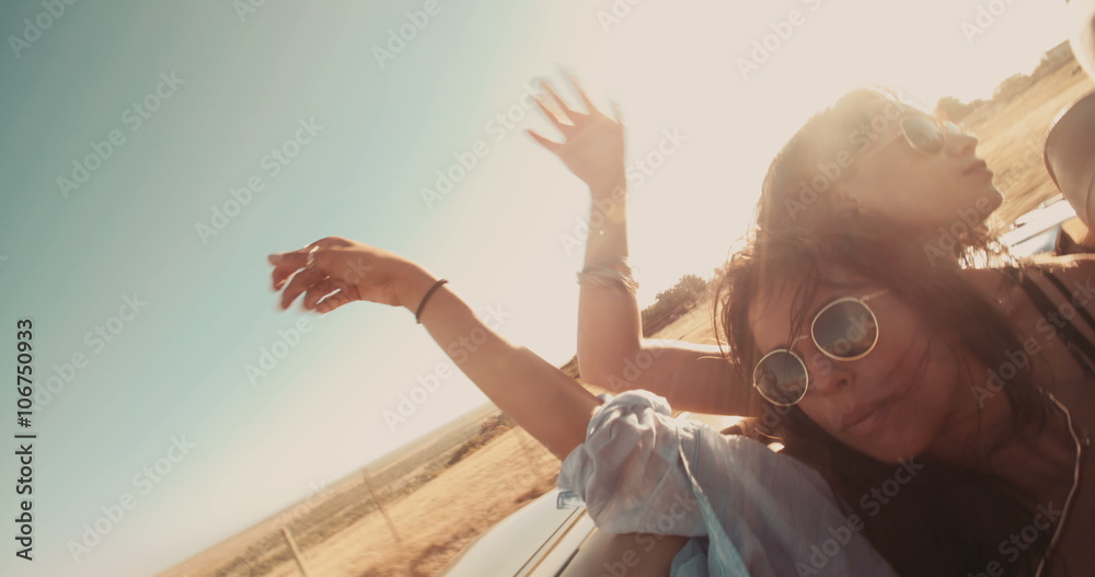 Teen friends laughing in a convertible during a road trip