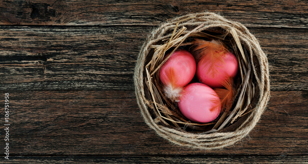 Easter pink eggs in nest on rustic wooden background