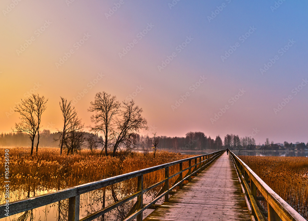 Lonely tourist crossing a bridge in the rays of dawn
