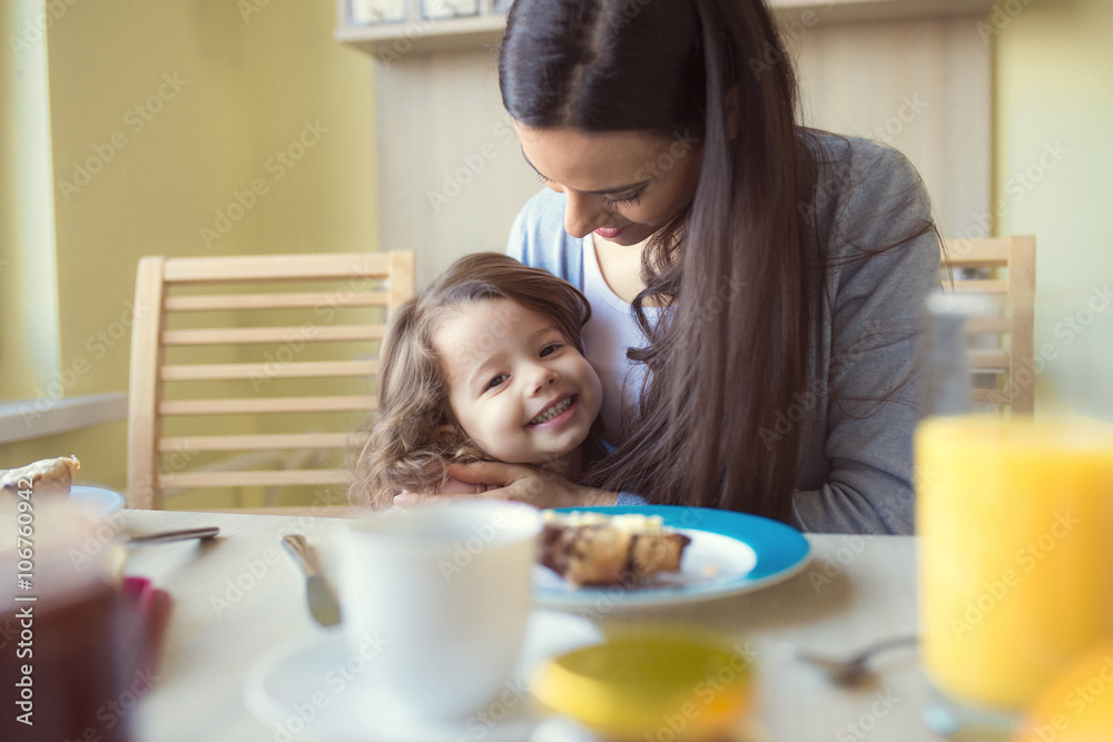 Portrait of smiling little girl and her mother at breakfast table Portrait of smiling little girl and her mother at breakfast table
