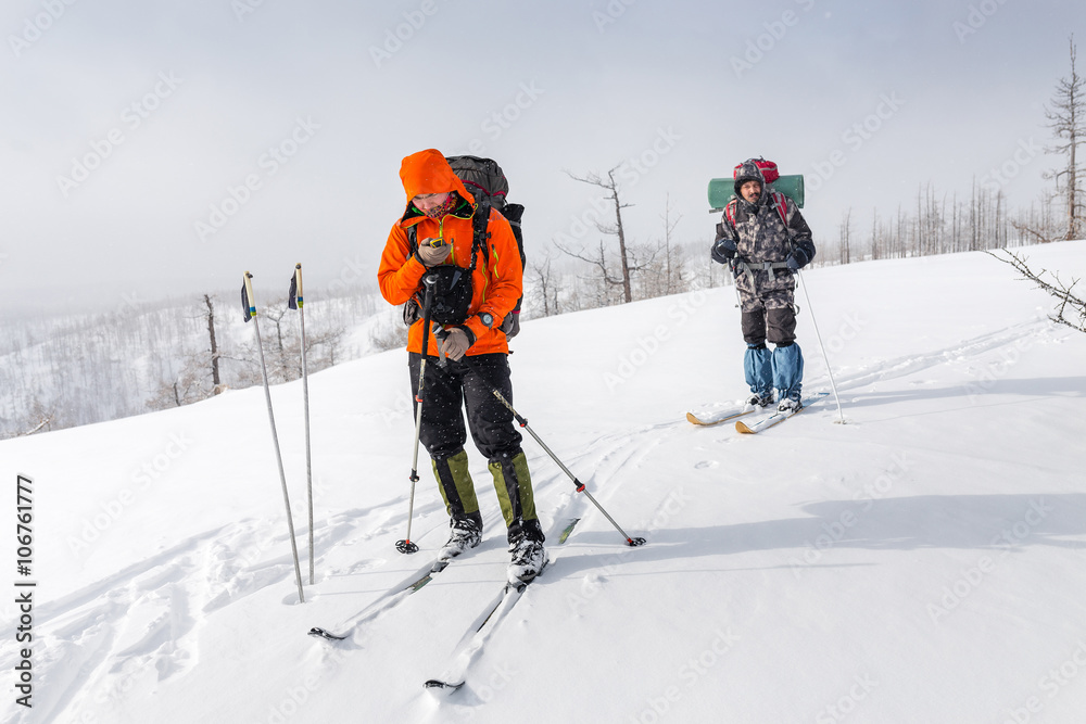 High altitude view of two skiers walking on a mountain ridge in