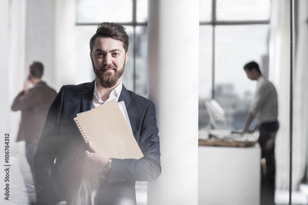 Portrait of smiling businessman holding a file in office Portrait of smiling businessman holding a file in office
