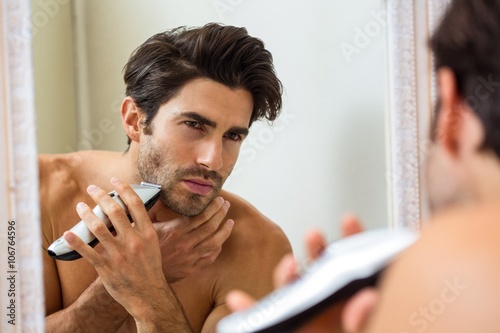 Young man shaving with trimmer