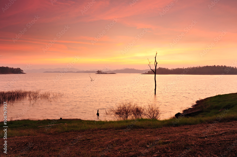 Obraz premium Cloud movement with dead trees on the dam at sunset Kanchanaburi.