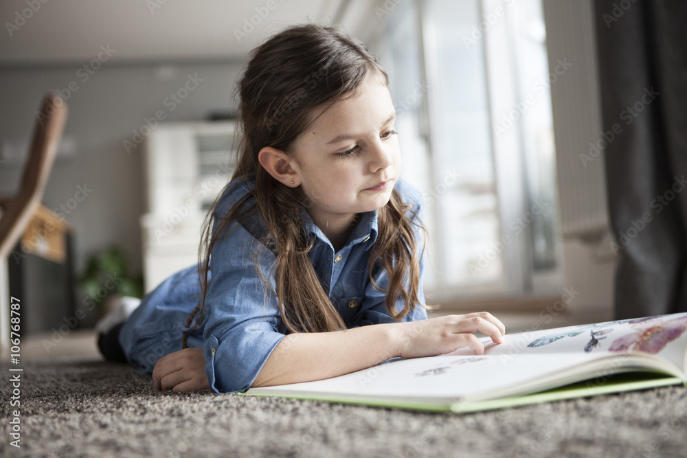 Portrait of little girl lying on the floor watching picture book Portrait of little girl lying on the floor watching picture book