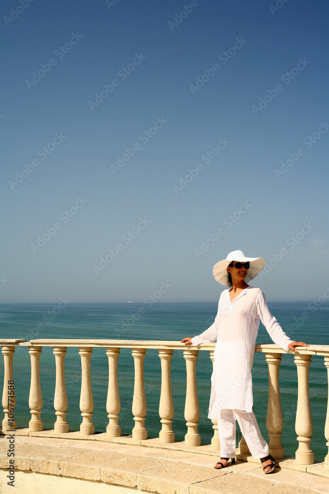femme habillée en blanc appuyée sur une rambarde