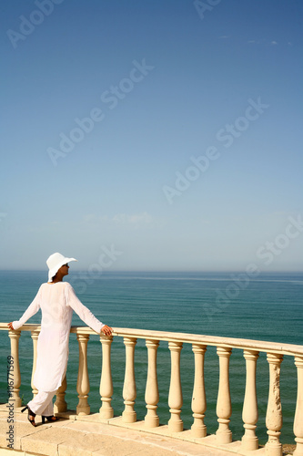 femme habillée en blanc sur une terrasse regardant au loin
