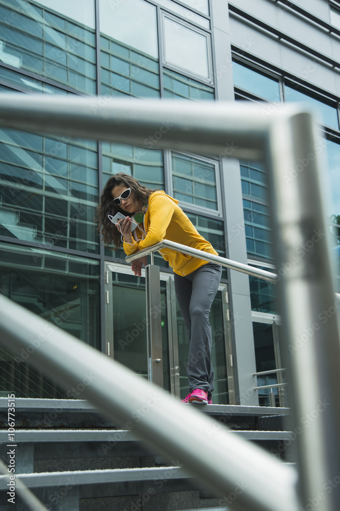 Young woman wearing yellow tracksuit top using smartphone Young woman wearing yellow tracksuit top using smartphone