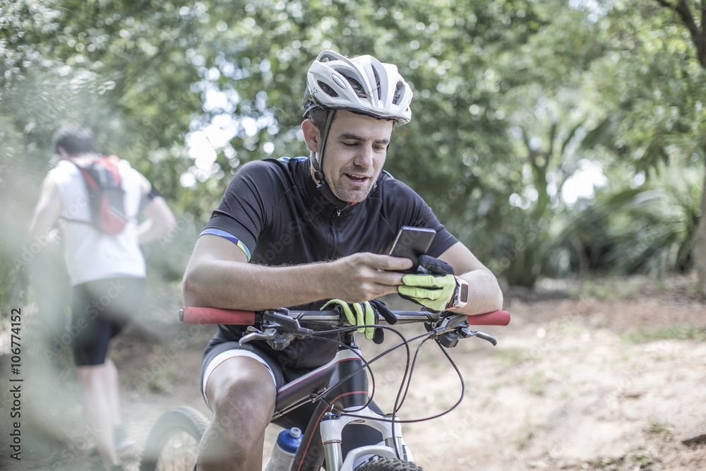 Man on mountain bike in forest looking at cell phone Man on mountain bike in forest looking at cell phone