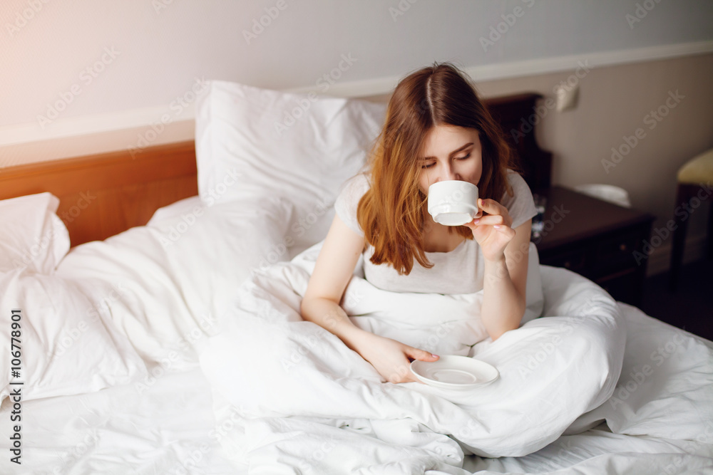 Beautiful woman drinking a coffee sitting on her bed home Beautiful woman drinking a coffee sitting on her bed home