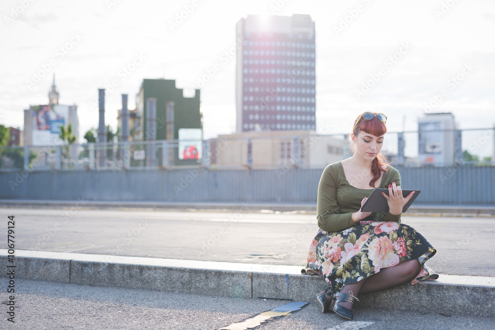 Young beautiful pin up redhead woman sitting on a sidewalk in th Young beautiful pin up redhead woman sitting on a sidewalk in th