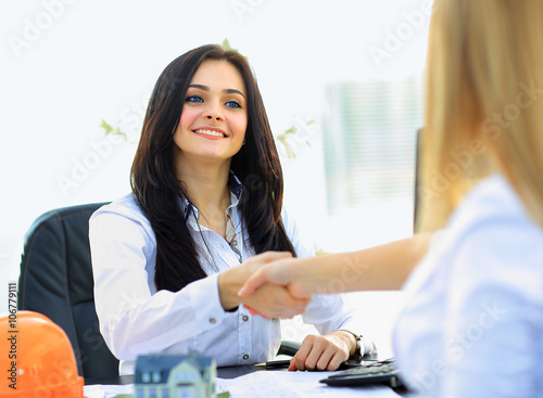 Two businesswomen shaking hands in modern office