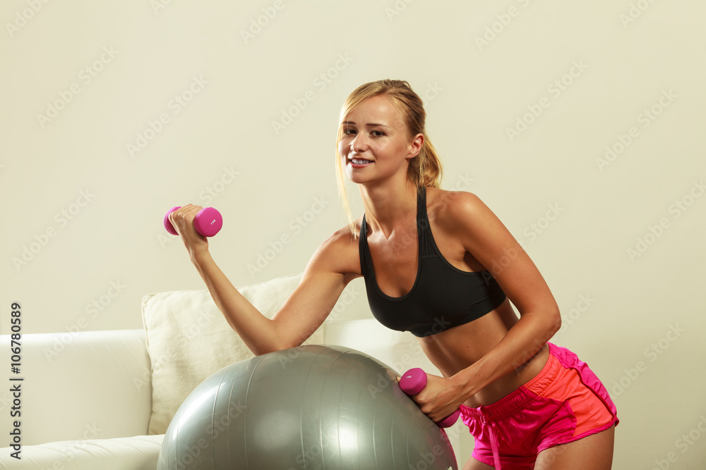 Woman with gym ball and dumbbell doing exercise Woman with gym ball and dumbbell doing exercise