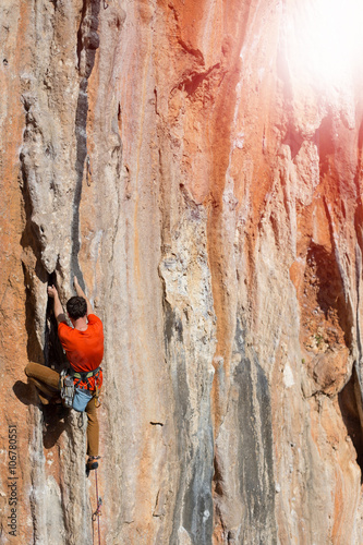 Athlete climbs on a rock against mountains.