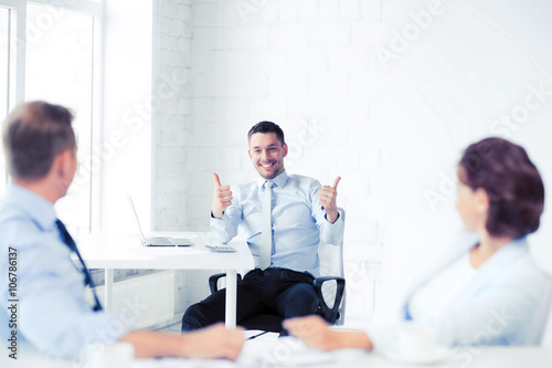 businessman showing thumbs up in office
