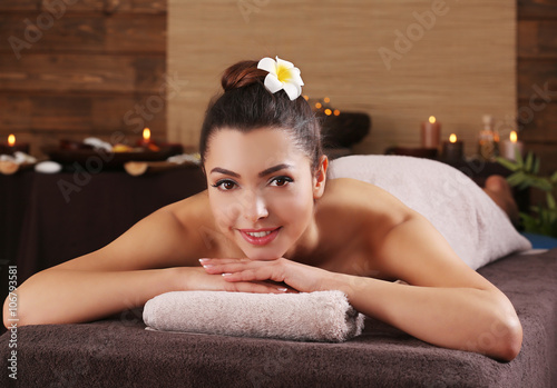 Beautiful young girl with towel lying on massage table in spa salon